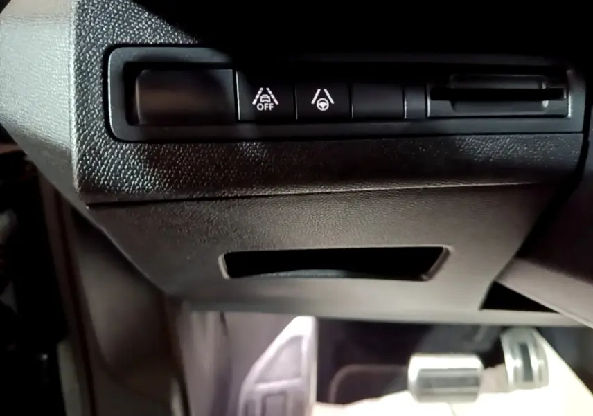 Vue rapprochée des commandes d'assistance à la conduite sous le tableau de bord noir du Peugeot 3008 GT bleu.