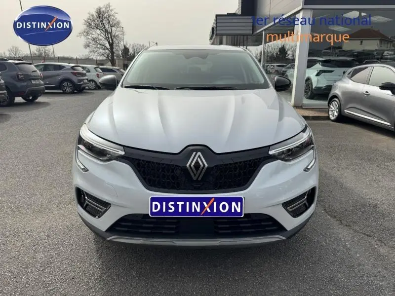 Vue avant d'un Renault Arkana blanc 2025 avec calandre noire et logo Renault bien visible, sur parking extérieur.