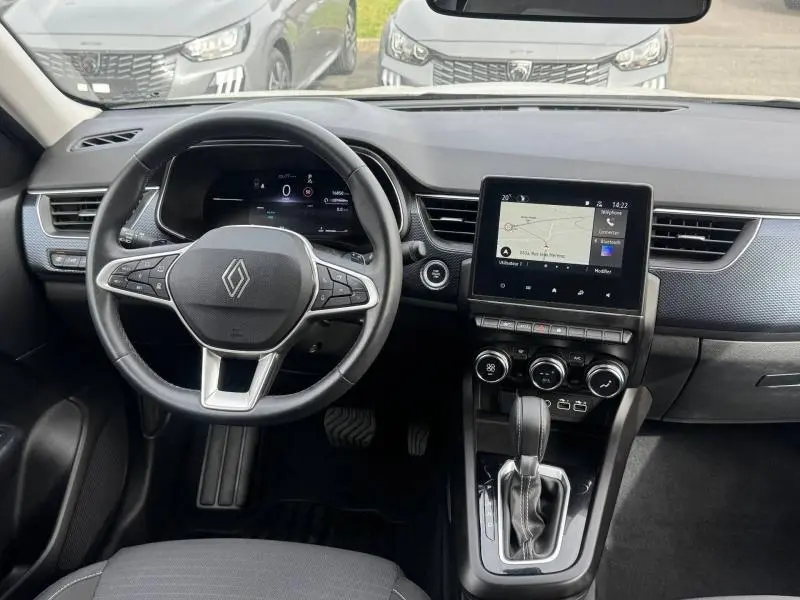 Vue intérieure frontale du tableau de bord et volant du Renault Arkana blanc 2025 avec écran tactile et commandes au volant.
