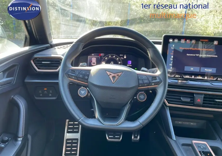 Vue intérieure centrée sur le volant cuir multifonction et l'écran tactile du tableau de bord d'une CUPRA Leon 2025.