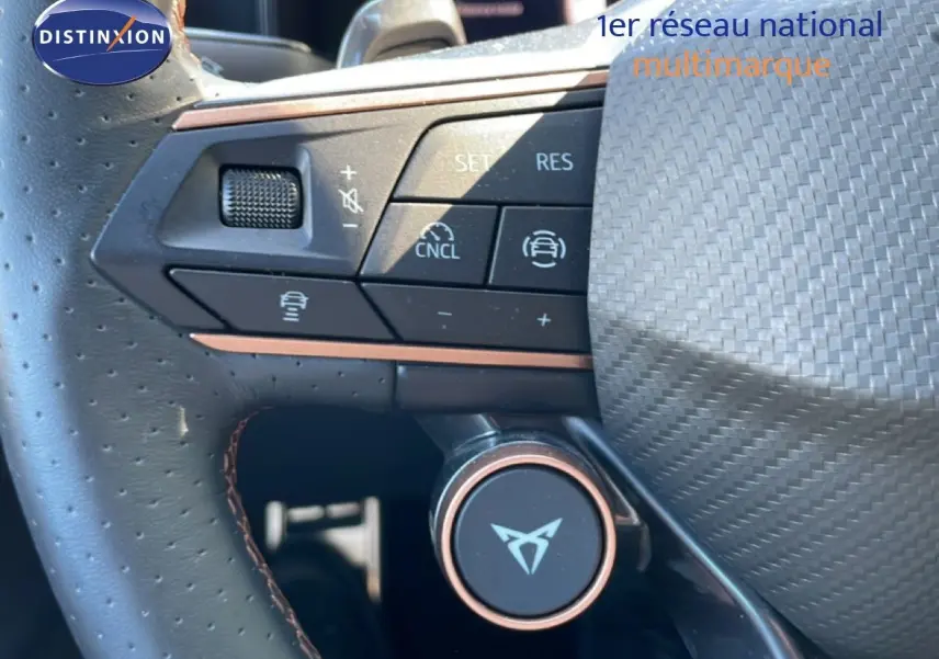 Gros plan sur le volant en cuir perforé du CUPRA Leon bleu Fjord, avec commandes multifonctions et logo CUPRA central.