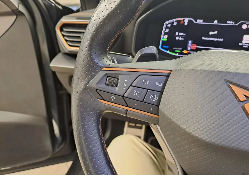 Gros plan sur le volant perforé du CUPRA Formentor 1.4 e-HYBRID 245 DSG6 VZ avec détails cuivre et tableau de bord numérique.