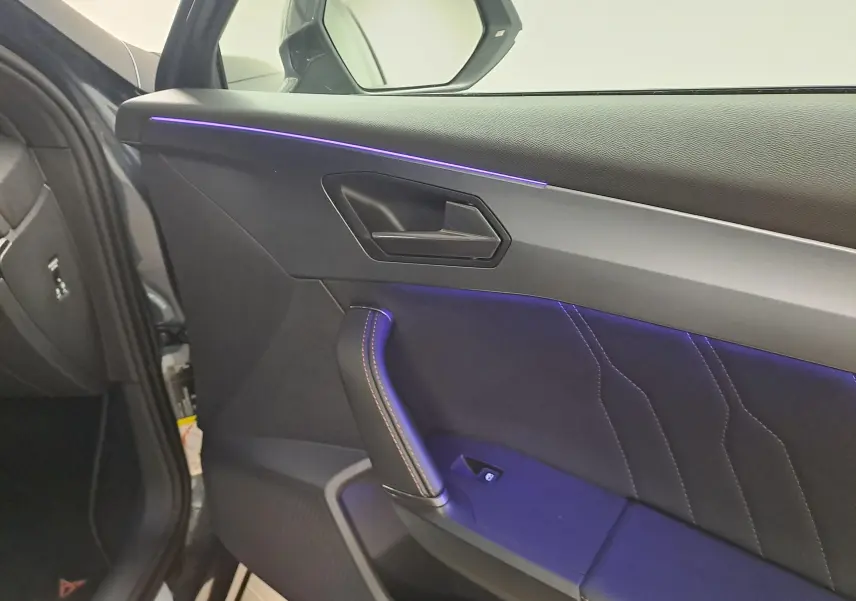 Vue intérieure côté gauche de la porte avant d'une CUPRA Formentor 1.4 e-HYBRID 2024 avec éclairage d'ambiance violet.