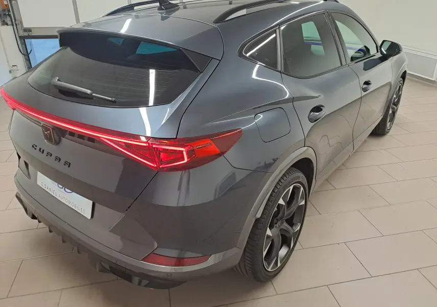 Vue 3/4 arrière droite du CUPRA Formentor 1.4 e-HYBRID 245 gris magnétique avec feux arrière allumés.