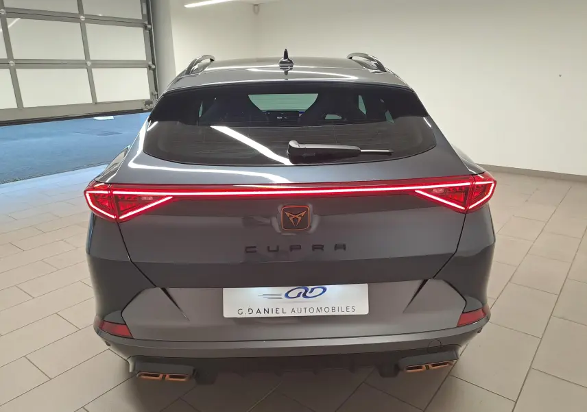 Vue arrière d'un CUPRA Formentor gris magnétique 2024 avec feux LED allumés et double sortie d'échappement cuivrée.