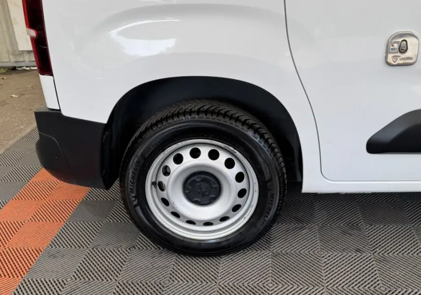 Gros plan sur la roue arrière droite blanche d’un Peugeot Partner 2021 avec jante acier et carrosserie blanche.