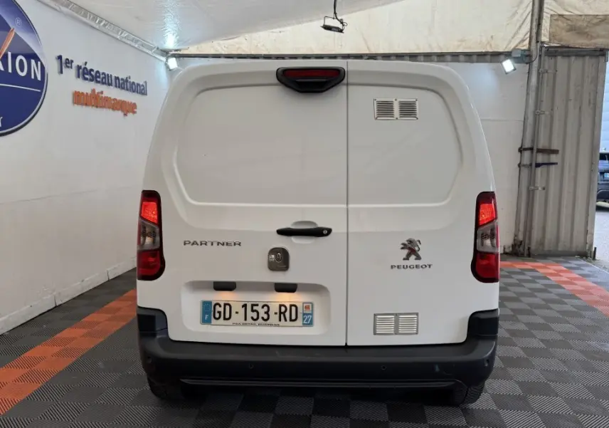 Vue arrière d’un utilitaire Peugeot Partner blanc avec feux arrière allumés et plaques d’immatriculation françaises.