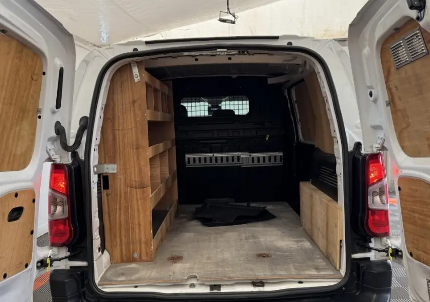 Vue arrière ouverte du Peugeot Partner blanc 2021 avec aménagements en bois dans l’espace de chargement.