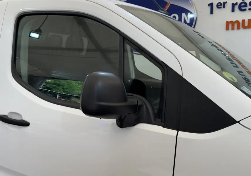 Vue latérale gauche rapprochée du Peugeot Partner blanc, mettant en valeur la portière et le rétroviseur noir.