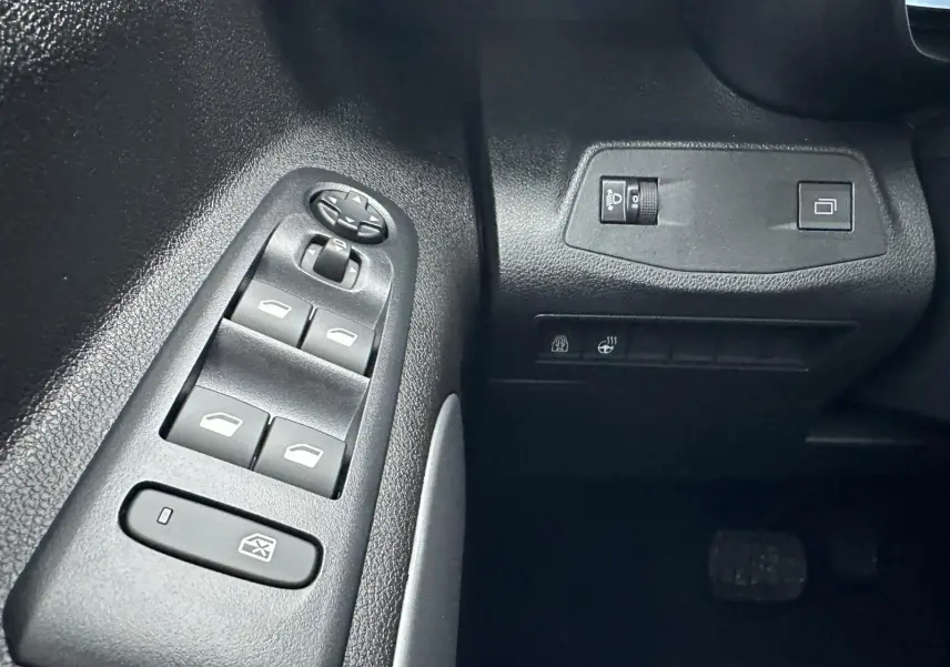 Gros plan sur les commandes de lève-vitres et réglage des rétroviseurs côté conducteur du Citroën Berlingo gris Artense 2025.