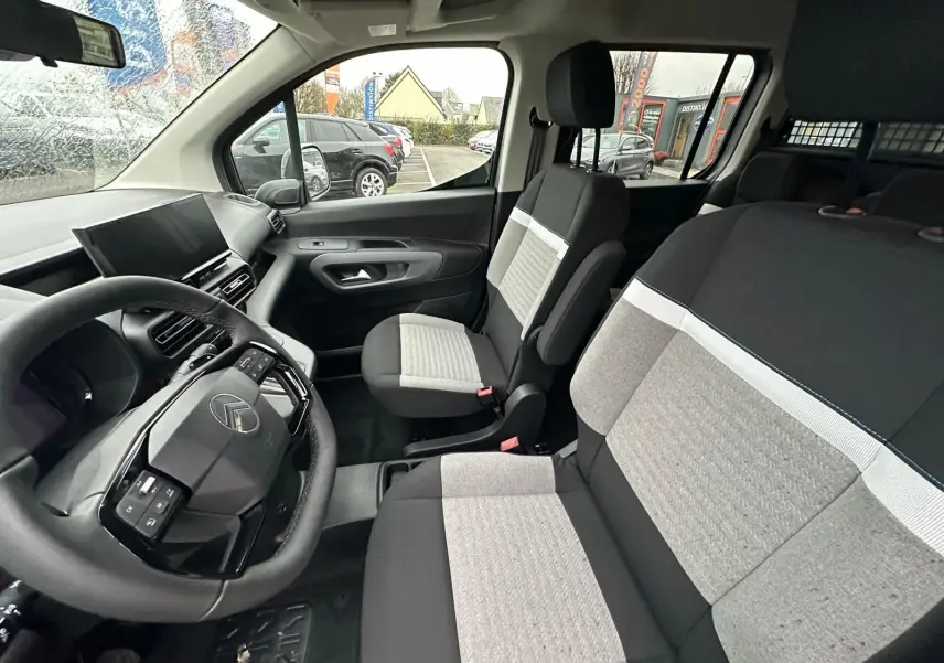 Vue intérieure côté conducteur du Citroën Berlingo 2025, sièges bicolores gris et noir avec tableau de bord moderne.