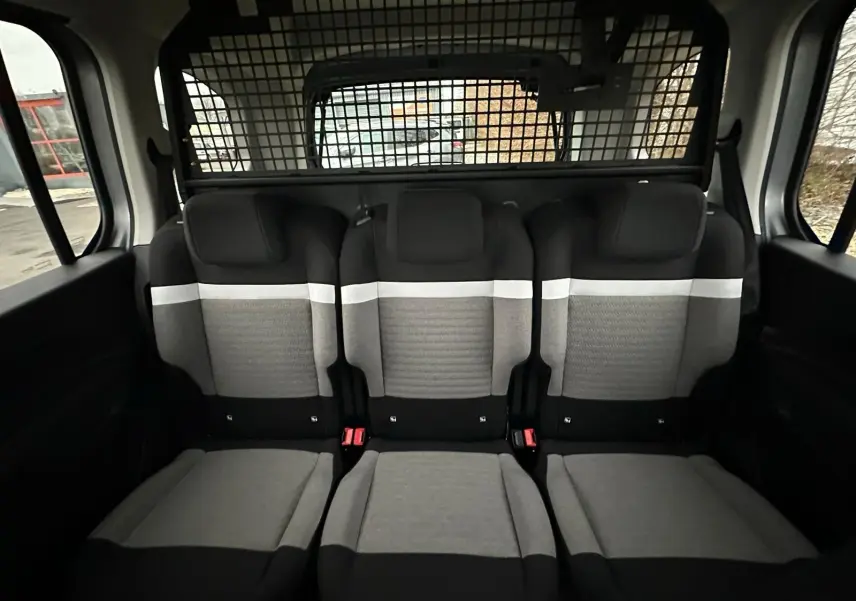 Vue intérieure arrière du Citroën Berlingo gris Artense, montrant les trois sièges arrière avec grille de séparation.