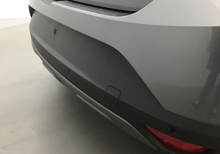 Gros plan sur le pare-chocs arrière gris schiste du Dacia Sandero Stepway 2025 avec feu et capteurs de recul visibles.