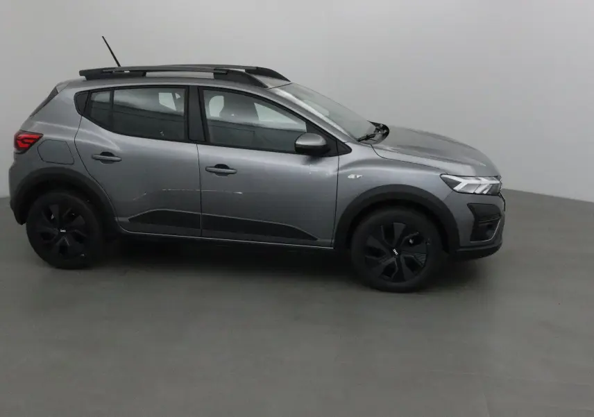 Profil côté gauche d'une Dacia Sandero Stepway gris schiste avec barres de toit et jantes noires.