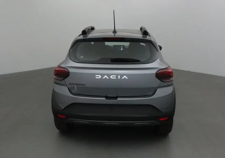 Vue arrière d'une Dacia Sandero Stepway 2025 en gris schiste avec barres de toit et feux arrière rouges.