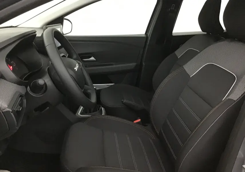 Intérieur côté conducteur de la Dacia Sandero Stepway 2025, montrant les sièges noirs avec surpiqûres et volant multifonction.