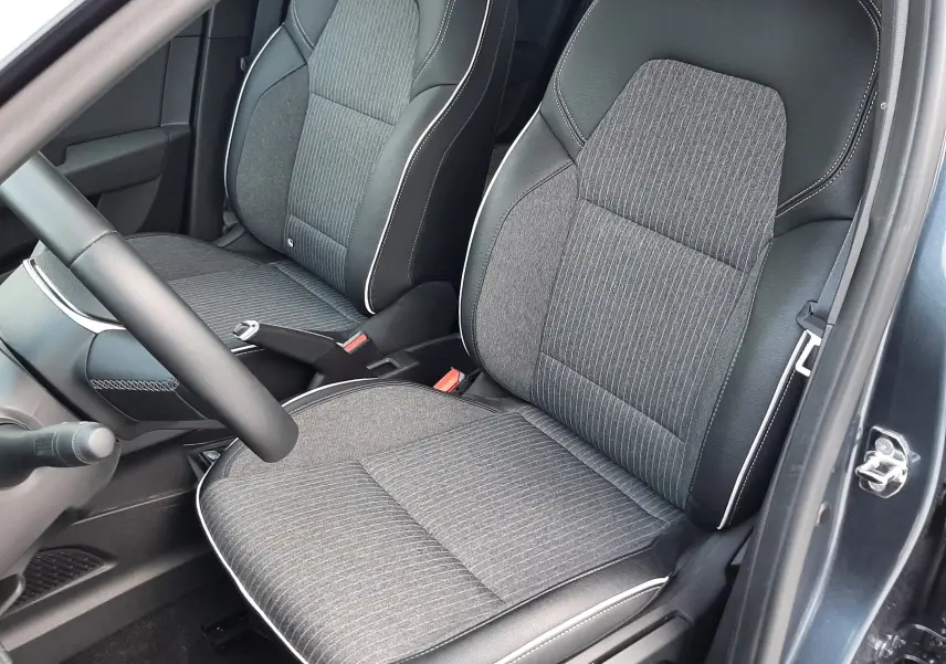 Vue intérieure côté conducteur de la Renault Clio V TCE 90 Intens avec sièges tissu gris et surpiqûres blanches.