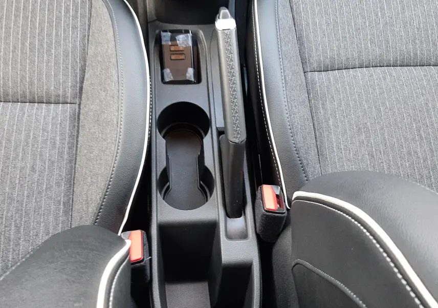 Vue plongeante sur la console centrale et les sièges gris tissu avec surpiqûres blanches d'une Renault Clio V 2021.