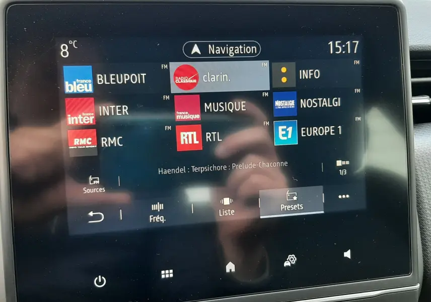 Écran tactile central de la Renault Clio V TCE 90 Intens X-Tronic gris titanium affichant les stations radio FM et la navigation à 15h17.
