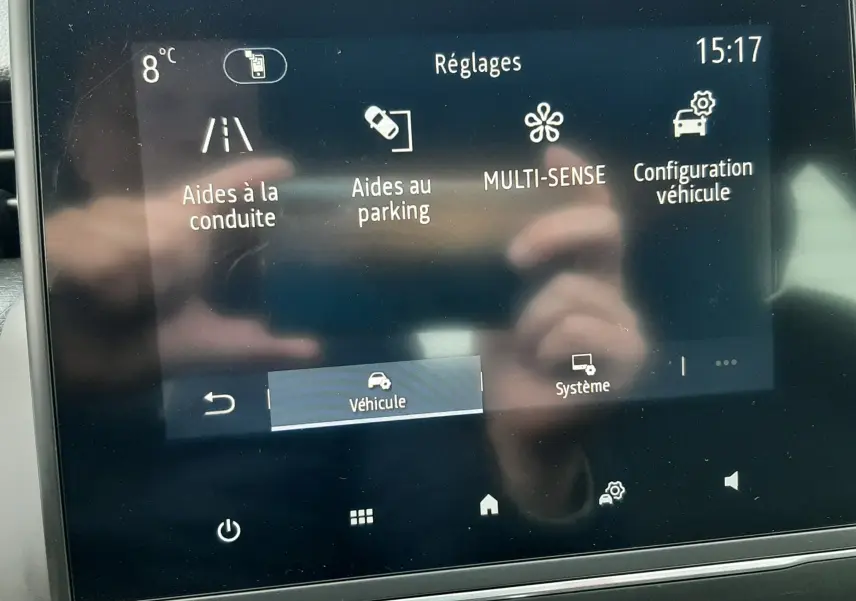 Écran tactile central de la Renault Clio V gris titanium montrant le menu Réglages avec aides à la conduite et parking.