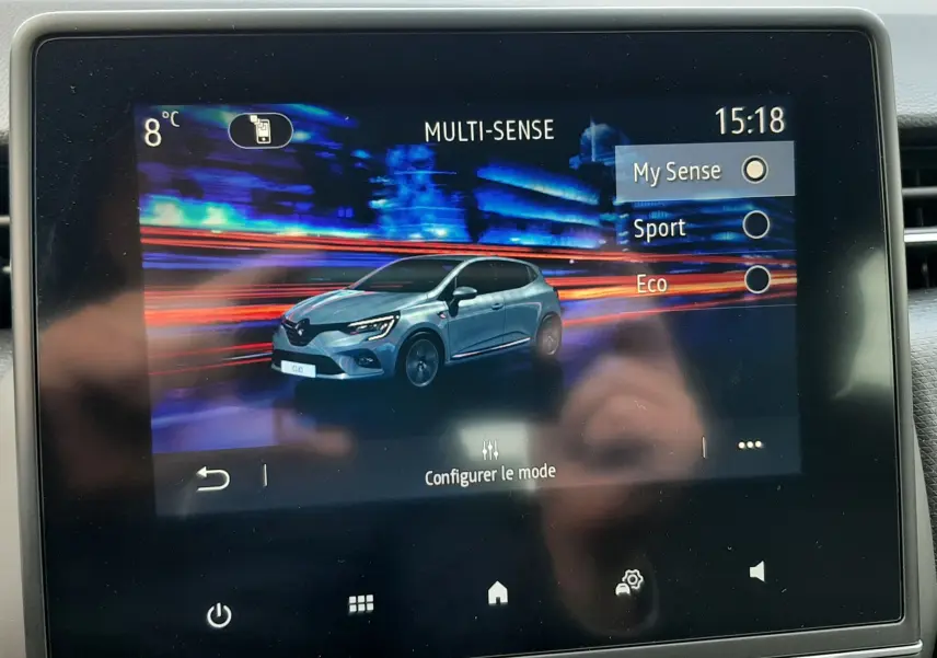 Écran tactile intérieur montrant une animation 3/4 avant d'une Renault Clio V gris titanium avec modes de conduite Multi-Sense.