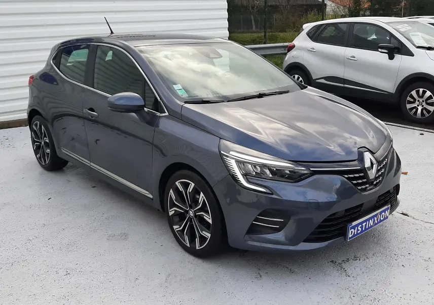 Renault Clio V TCE 90 Intens gris titanium vue 3/4 avant droit, avec jantes alliage et feux LED allumés.