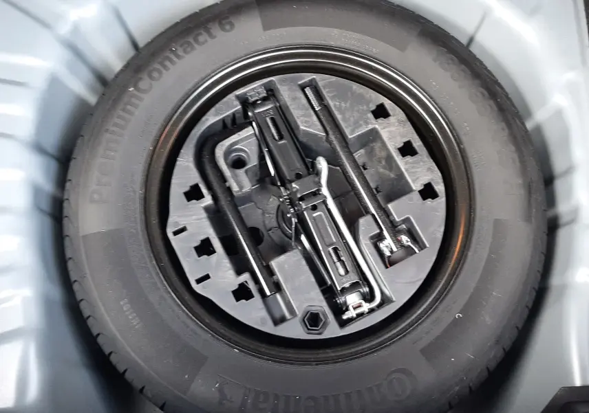 Gros plan sur la roue de secours et les outils de bord dans le coffre d'une Renault Clio V gris titanium.