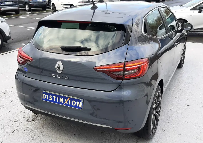 Vue 3/4 arrière droite d'une Renault Clio V gris titanium avec feux LED et jantes alliage biton sur parking.