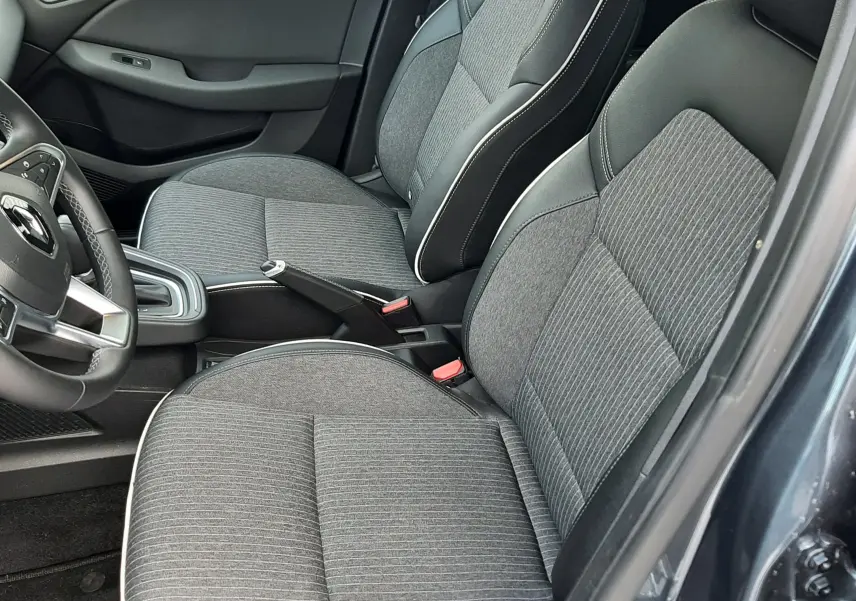 Intérieur de la Renault Clio V TCE 90 Intens gris titanium, vue côté conducteur sur sièges tissu et cuir avec surpiqûres blanches.