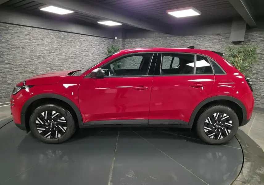 Profil côté gauche d'une FIAT 600 1.2 Hybrid rouge vif avec jantes 16'' bicolores et coques de rétroviseurs noires.