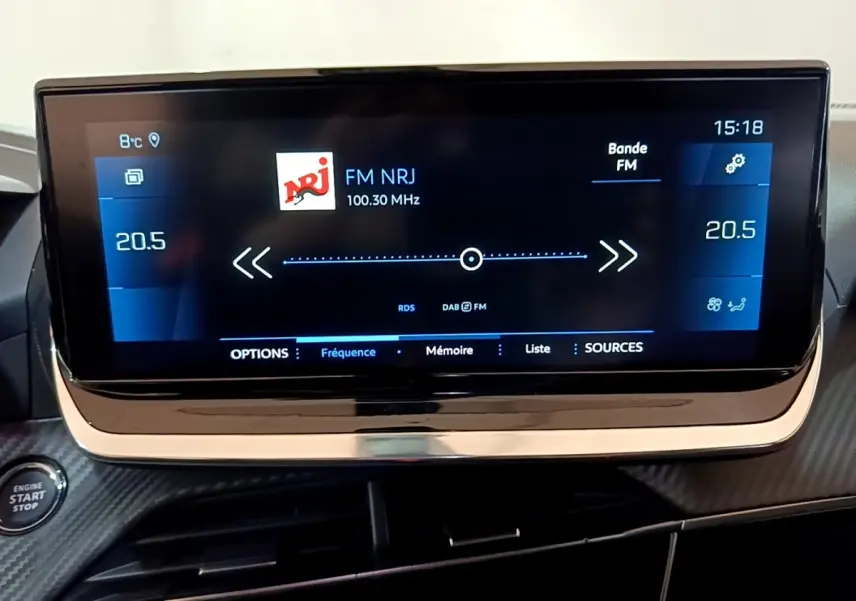 Écran tactile central de 10 pouces affichant la radio FM NRJ dans l’habitacle du Peugeot 2008 orange.