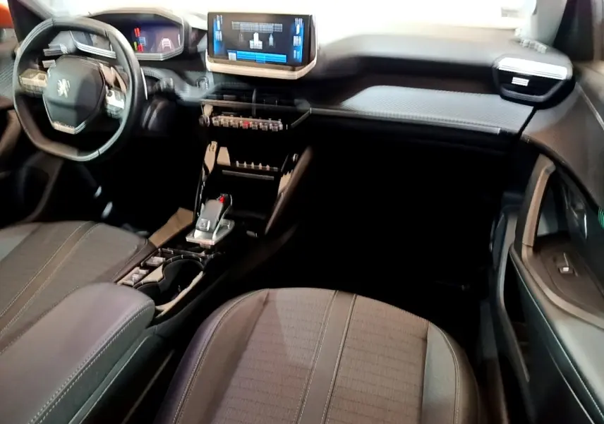 Vue intérieure avant droite du Peugeot 2008, tableau de bord moderne avec écran tactile et volant multifonctions noir.