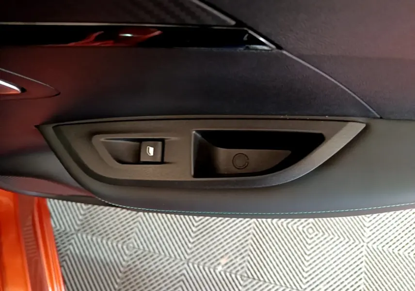 Détail de la poignée intérieure de porte côté gauche d’un Peugeot 2008 orange, avec bouton de verrouillage.