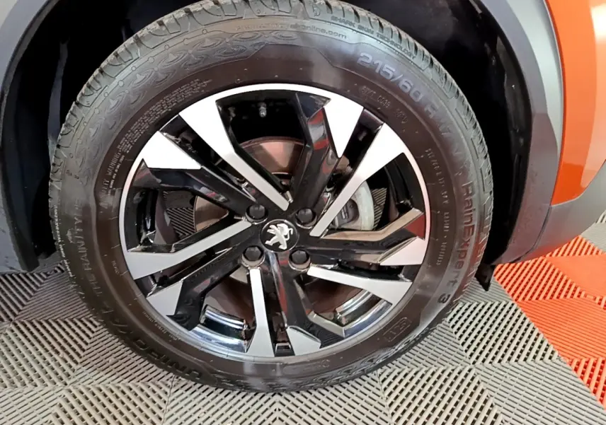 Gros plan sur la roue avant droite du Peugeot 2008 orange, mettant en valeur la jante alliage bicolore et le logo lion.