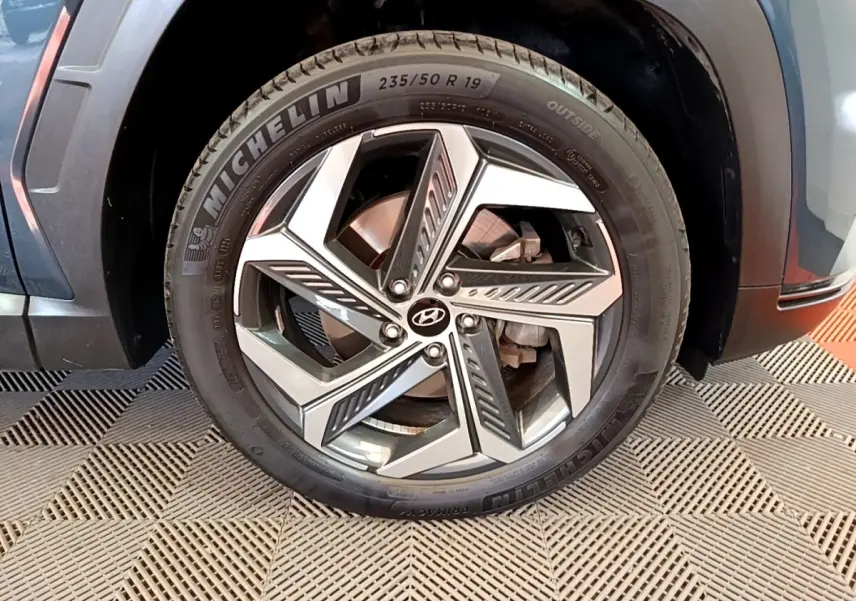 Gros plan sur la roue avant droite du Hyundai Tucson bleu 2023 avec jante alliage et pneu Michelin.