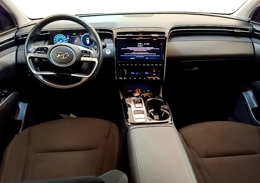 Vue intérieure avant du Hyundai Tucson 2023, tableau de bord noir avec écran tactile central et volant multifonctions.