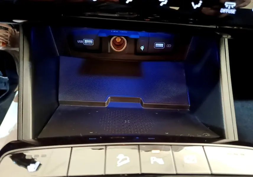 Vue rapprochée de la zone de recharge par induction et ports USB du Hyundai Tucson bleu 2023, avec boutons de commande en bas.