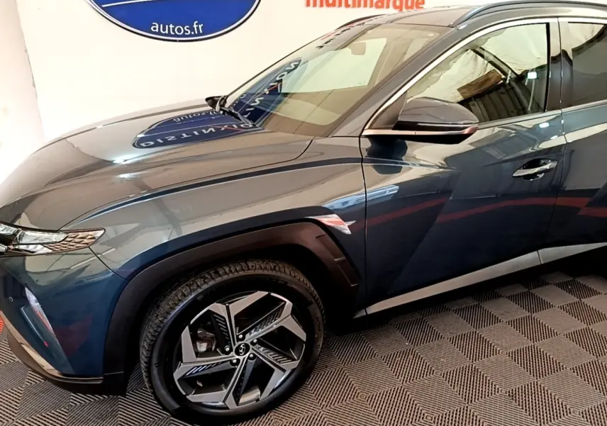 Vue de profil côté gauche d'un Hyundai Tucson bleu 2023 avec jantes alliage et rétroviseur noir brillant.
