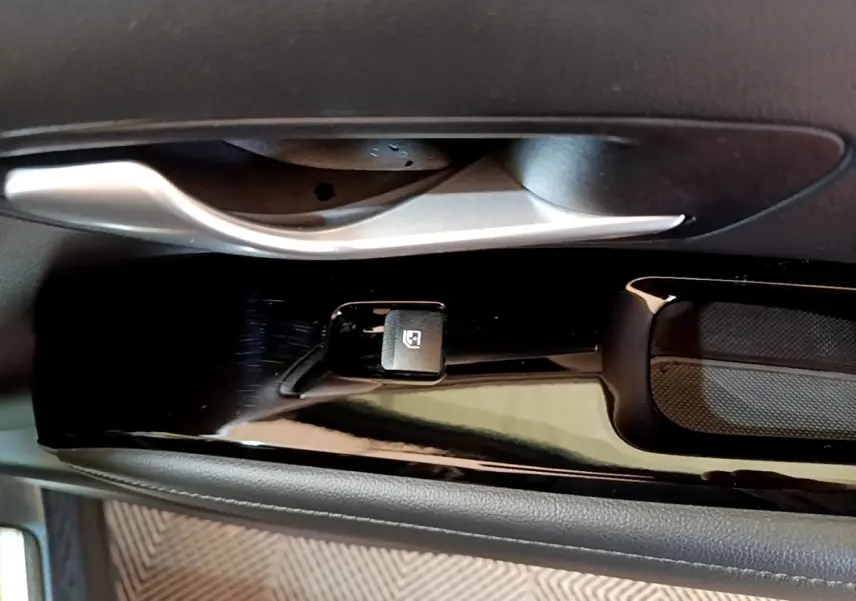 Gros plan sur la commande de lève-vitre côté conducteur du Hyundai Tucson bleu, avec poignée de porte argentée.