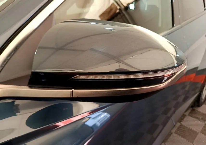 Rétroviseur côté droit bleu du Hyundai Tucson 2023 avec clignotant intégré, vue rapprochée en extérieur.
