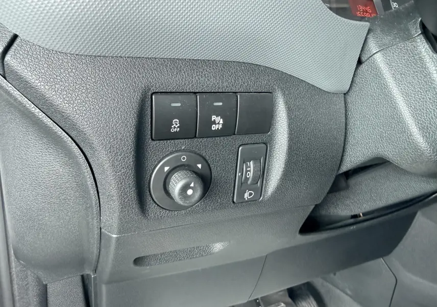 Détail des commandes de réglage des rétroviseurs et des feux sur le côté gauche du tableau de bord d’un Citroën Berlingo blanc.