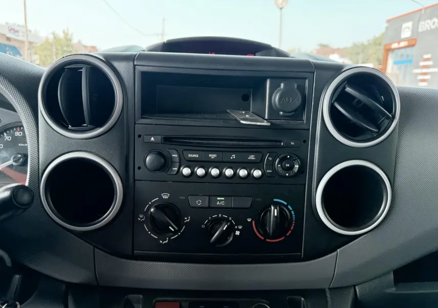 Tableau de bord central noir du Citroën Berlingo 2016 avec commandes de climatisation et lecteur audio, vue frontale rapprochée.