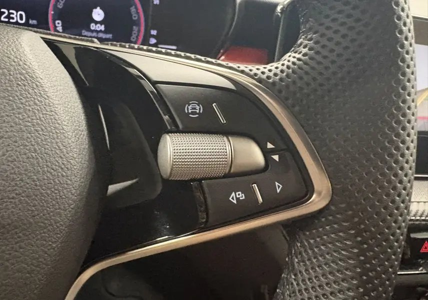 Gros plan sur les commandes gauche du volant perforé de la Skoda Fabia 2025, finition Monte Carlo, avec molette argentée.