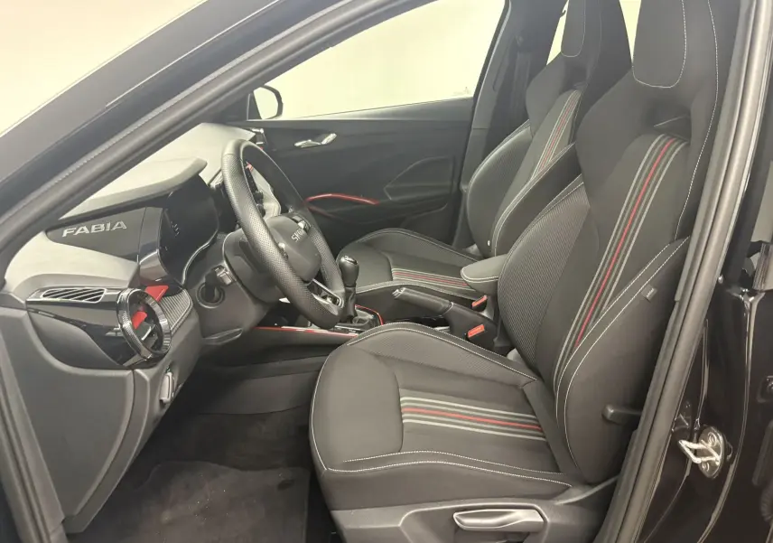 Vue intérieure côté conducteur de la Skoda Fabia Monte Carlo 2025 avec sièges noirs à bandes rouges et tableau de bord marqué Fabia.