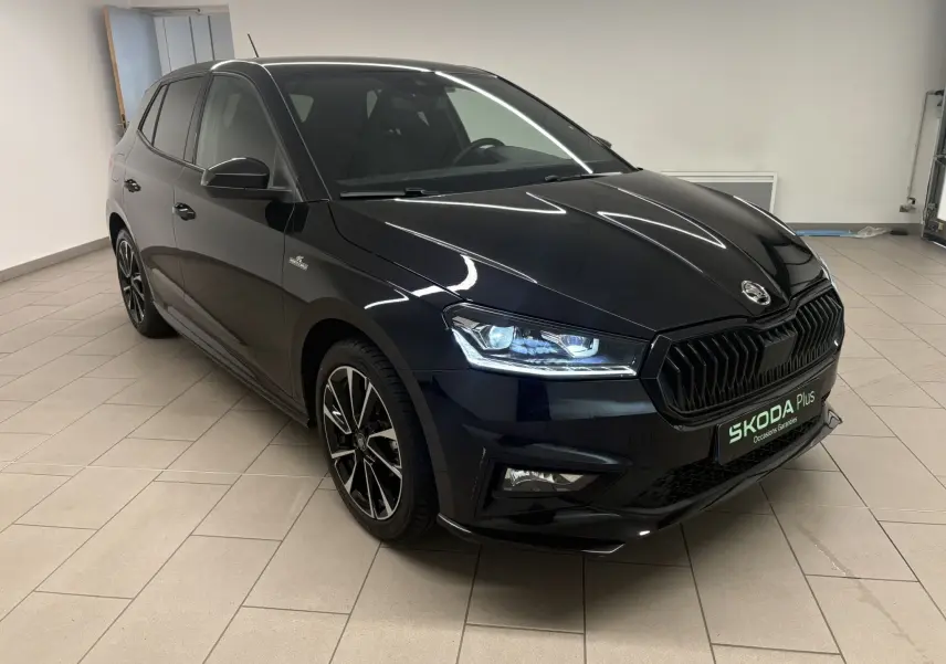 Vue 3/4 avant gauche d'une Skoda Fabia Monte Carlo 2025 en noir Magic nacré avec jantes noires et phares LED allumés.