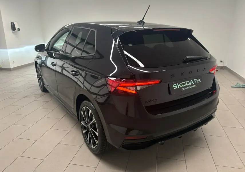 Vue 3/4 arrière droite de la Skoda Fabia 2025 noire nacrée, avec feux allumés et jantes sportives visibles.