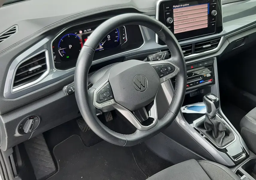 Vue intérieure du poste de conduite du Volkswagen T-Roc 2.0 TDI 2022, volant multifonction et écran tactile central allumé.