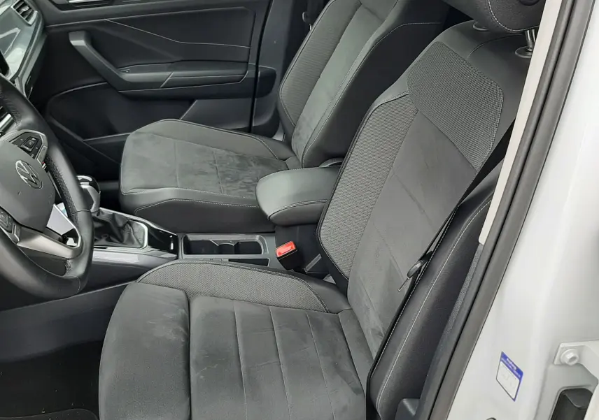 Vue intérieure côté conducteur du Volkswagen T-Roc blanc pur 2022, sièges tissu noir avec accoudoir central.