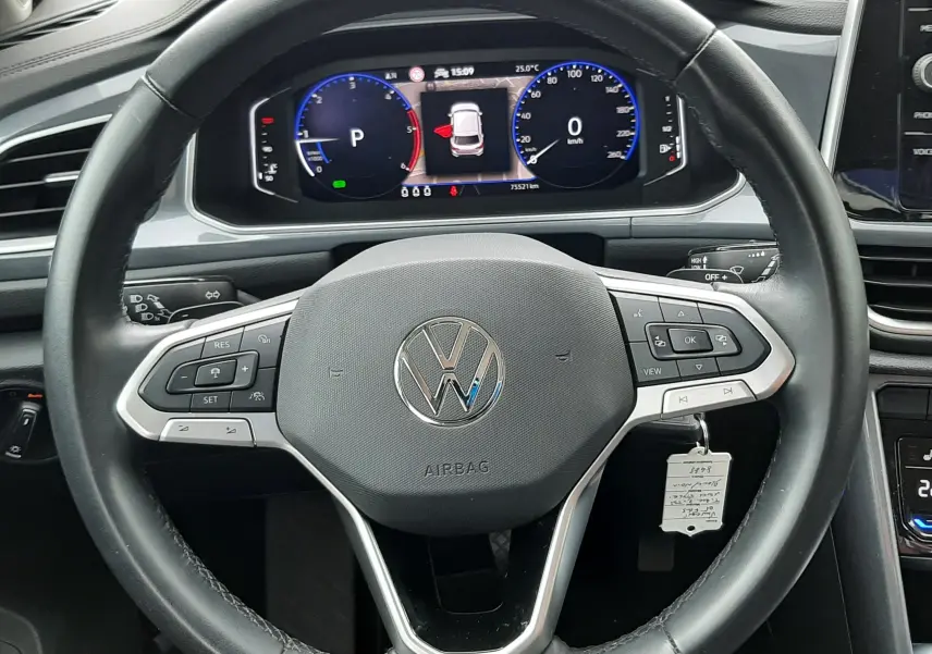 Vue rapprochée du volant noir du Volkswagen T-Roc 2022 avec tableau de bord numérique allumé.