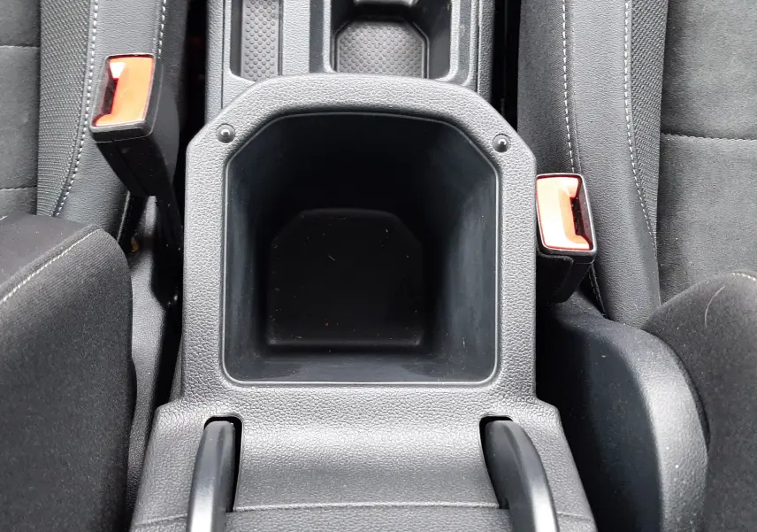 Vue plongeante sur le rangement central noir entre les sièges avant du Volkswagen T-Roc 2.0 TDI 150CH Style DSG7, intérieur tissu noir.
